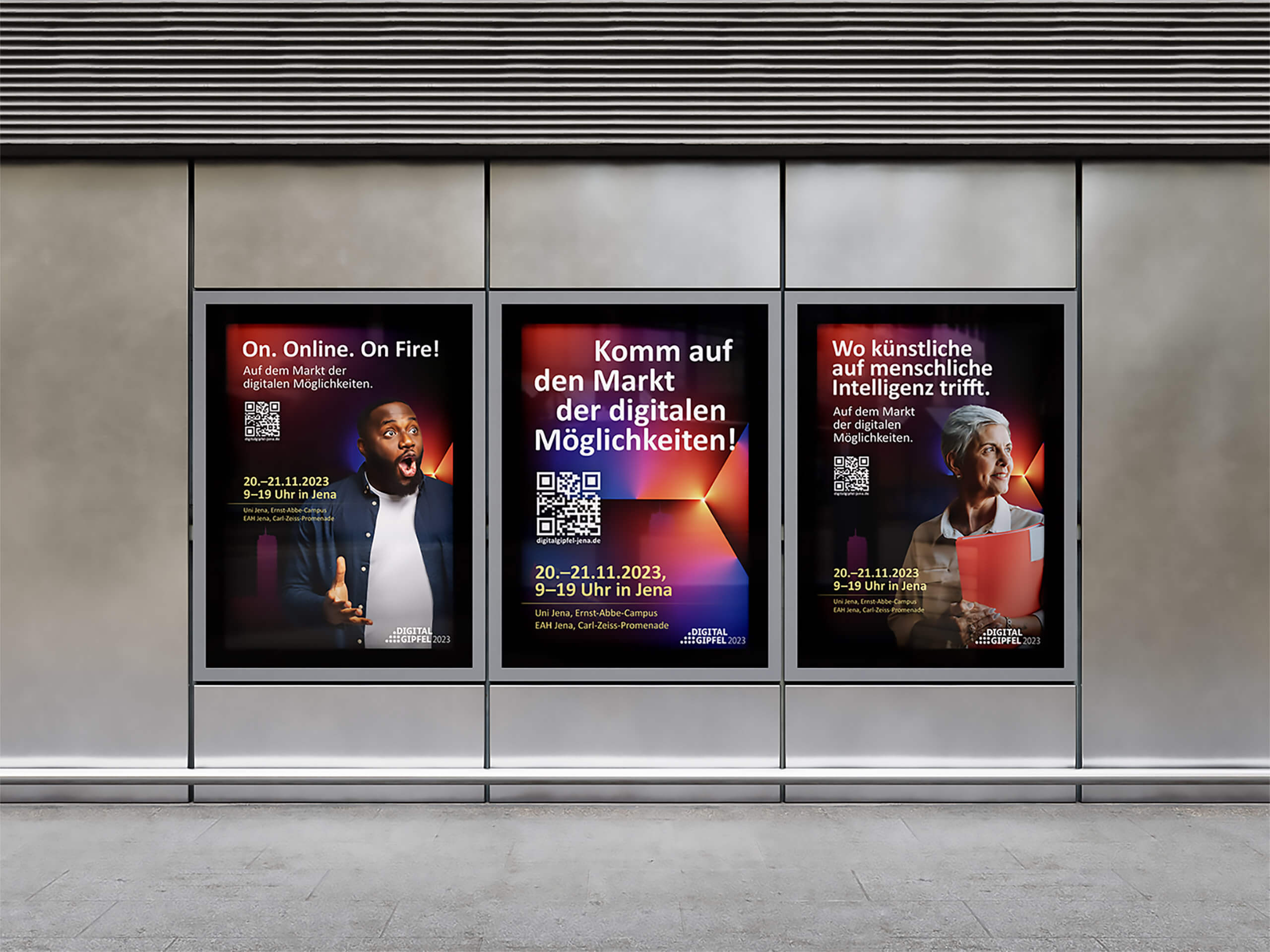 Drei beleuchtete Plakate an einer Wand werben für ein Event zum Thema digitale Möglichkeiten in Jena. Sie zeigen verschiedene Personen, Headlines, QR-Codes sowie Datum und Veranstaltungsinformationen