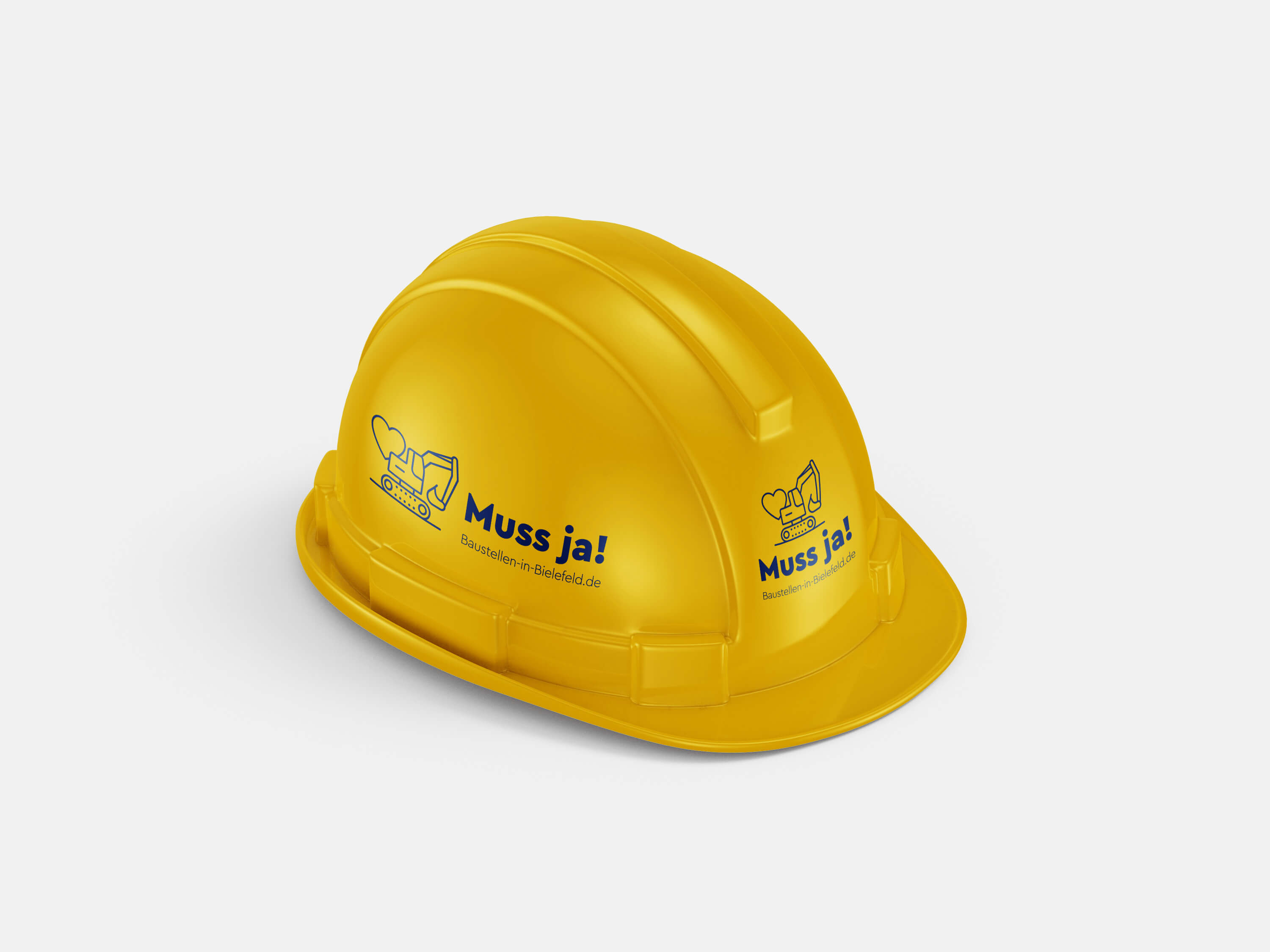 Gelber Bauhelm mit Logo der Kampagne „Muss ja!“ zur Baustellenkommunikation und Imagearbeit in Bielefeld