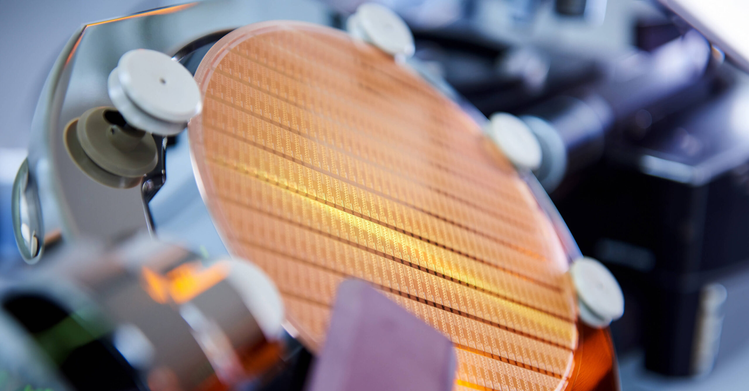 Nahaufnahme eines Silizium-Wafers in einer Halterung innerhalb einer Produktionsanlage für Mikrochips, sichtbar sind feine Strukturen der Halbleiterfertigung in einer Hightech-Umgebung