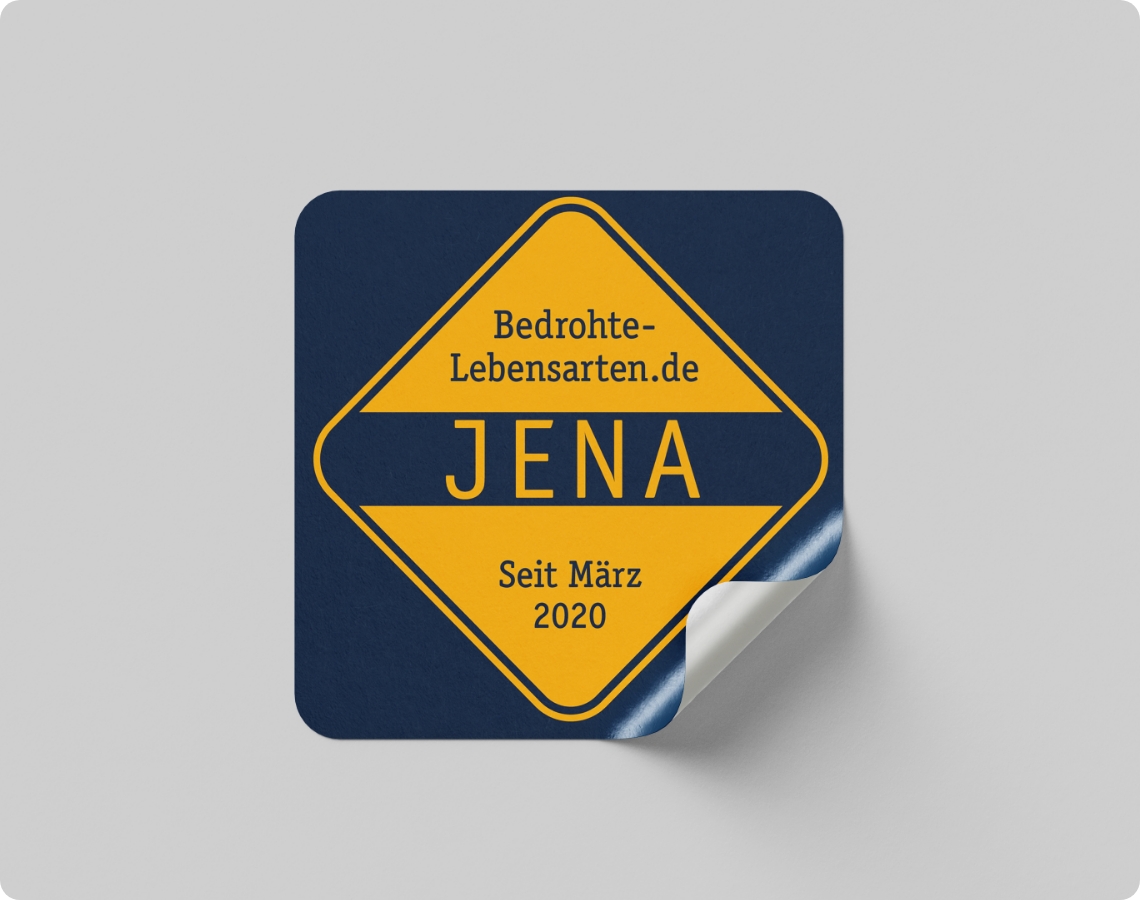 Quadratischer Aufkleber im Stil eines Verkehrsschilds in Blau und Gelb mit der Aufschrift „Bedrohte-Lebensarten.de JENA Seit März 2020“