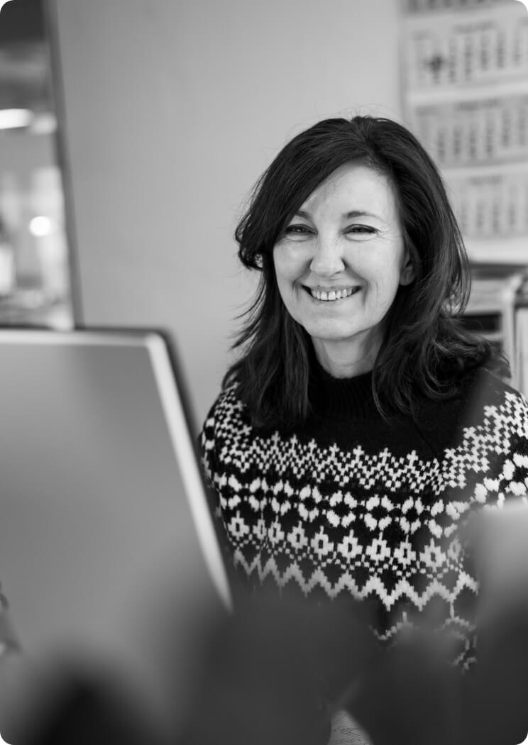 Porträt einer lächelnden Mitarbeiterin am Computer im Büro als Bildmotiv für Teamarbeit und Arbeitsalltag