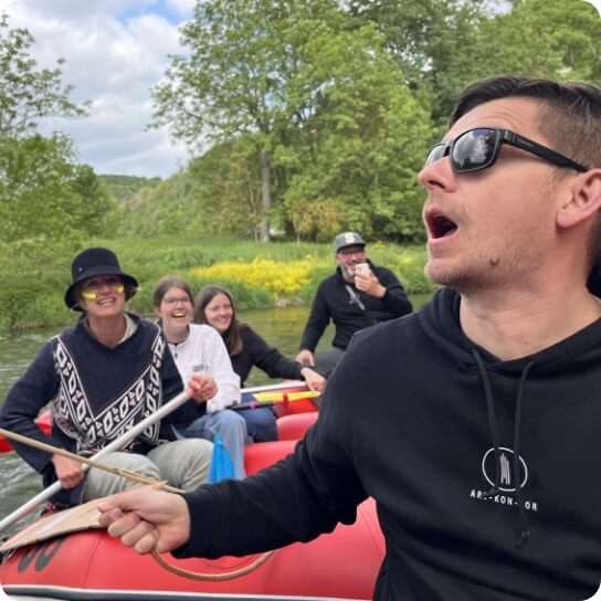 36 Teammitglieder bei Kanutour auf Fluss mit humorvoller Szene als Bildmotiv für Teambuilding und gemeinsame Erlebnisse