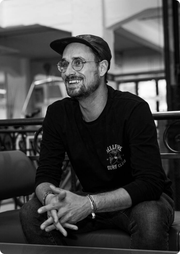 Porträt eines Mitarbeiters mit Brille und Cap im Büro als Bildmotiv für Teamvorstellung und Unternehmenskultur