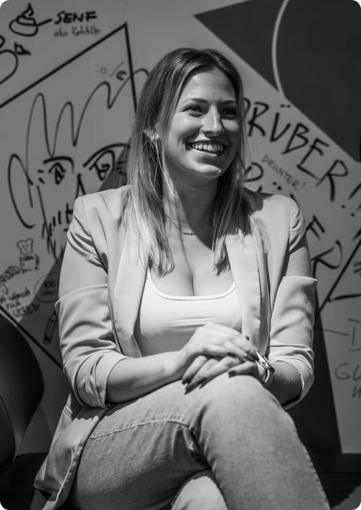 Porträt einer lächelnden Frau vor Kreativwand als Bildmotiv für Teamarbeit und Agenturkultur
