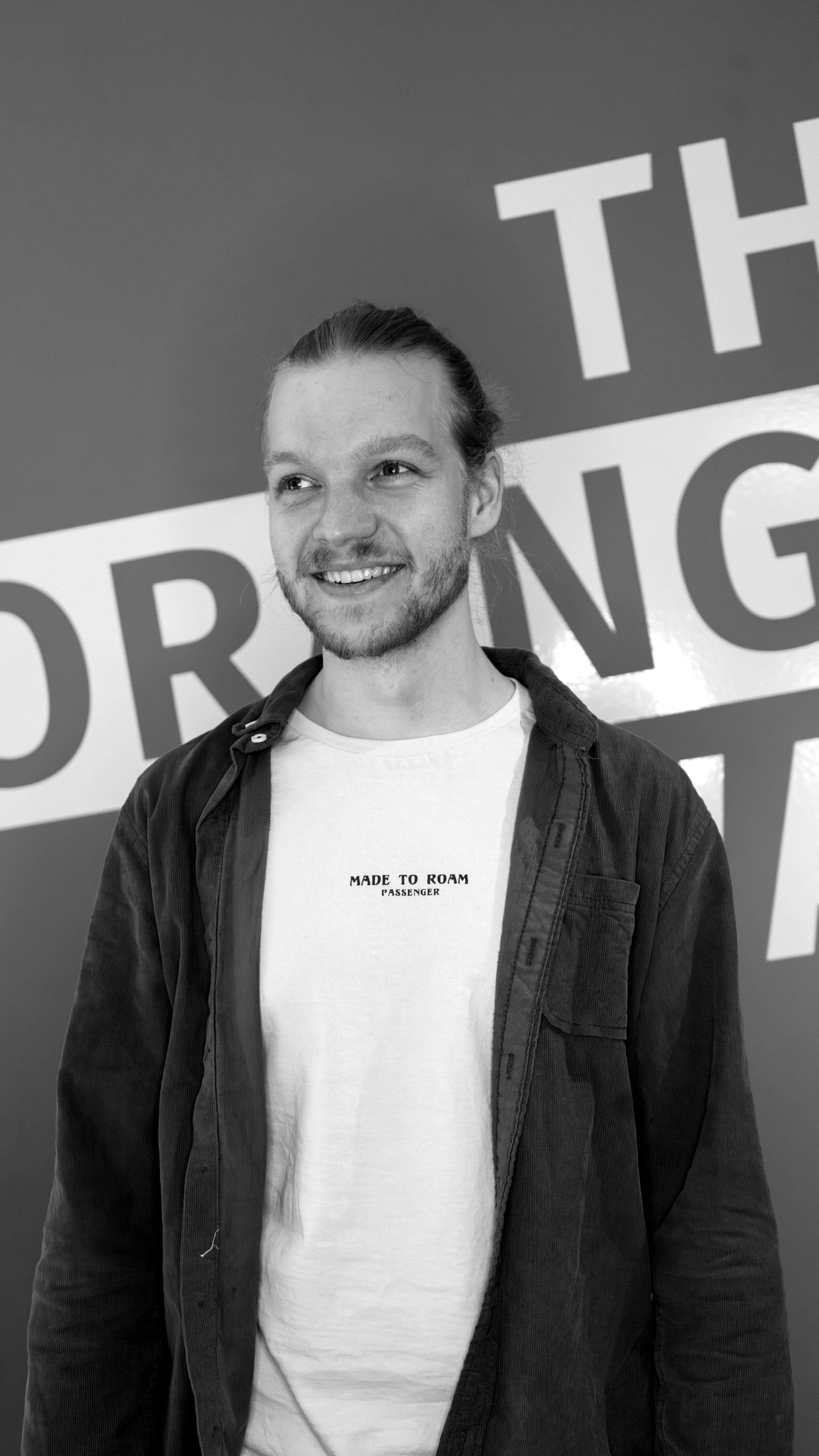 Porträt eines jungen Mannes vor Unternehmensbranding als Bildmotiv für Teamvorstellung und Arbeitgebermarke