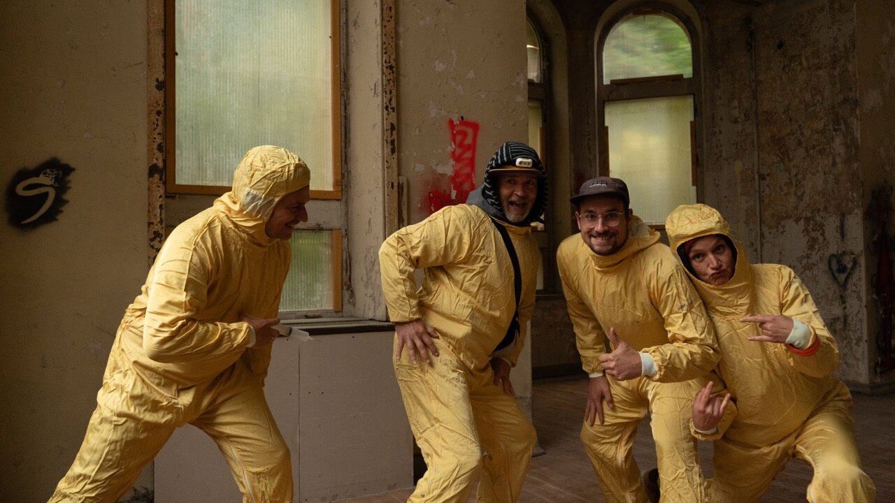 Teammitglieder in Schutzanzügen bei kreativem Teamevent in Industriegebäude als Bildmotiv für Teamkultur und Agenturalltag